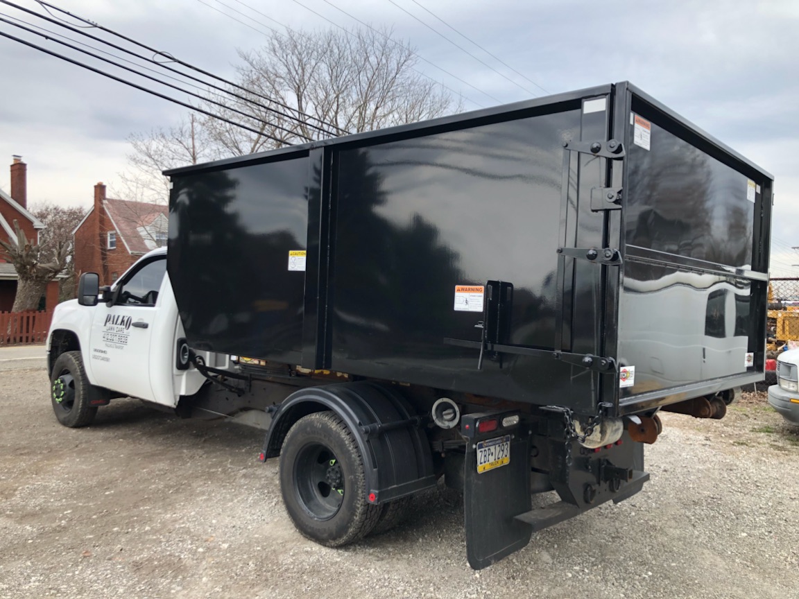 Black dumpster on the back of a truck